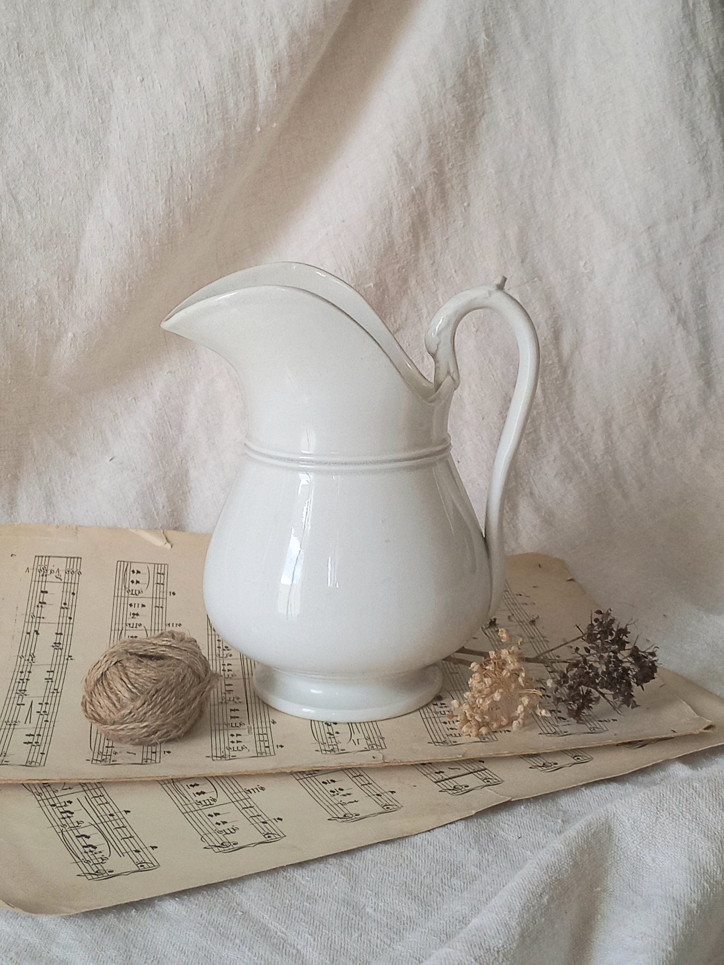 French antique white ironstone jug or pitcher with swan neck handle in a decorative setting.