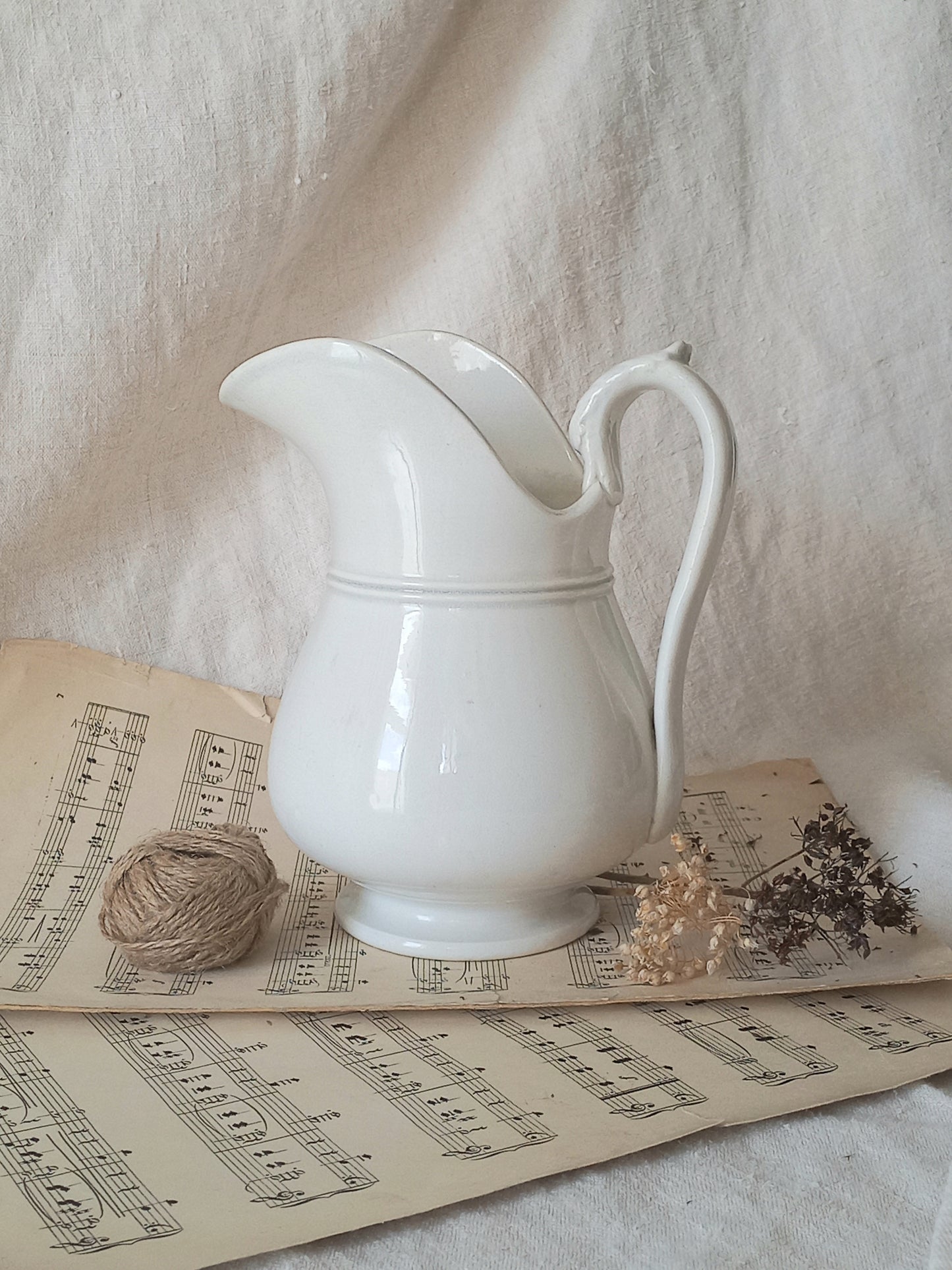  French antique white ironstone jug or pitcher with swan neck handle in a decorative setting.
