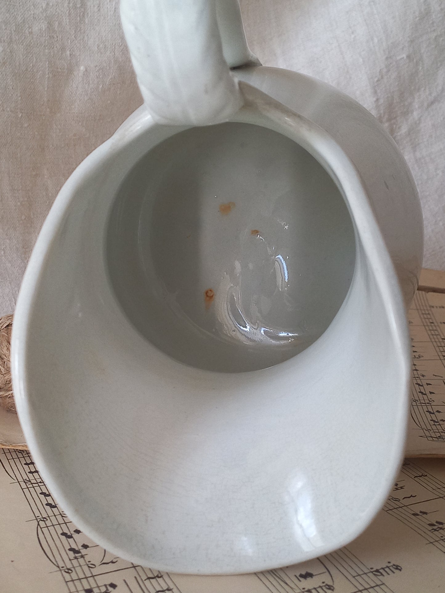 Close-up of a French antique white ironstone jug or pitcher with swan neck handle in a decorative setting.