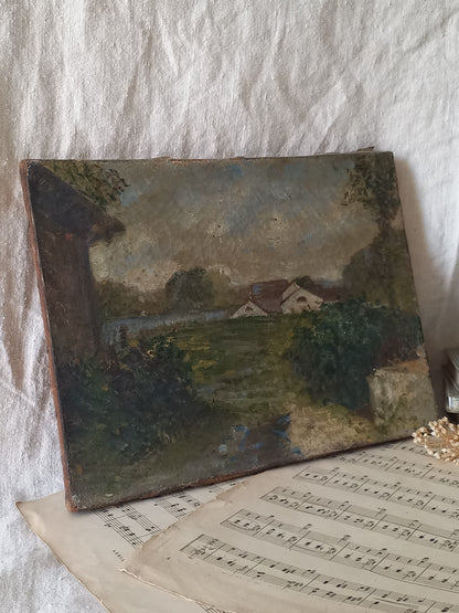 An antique landscape oil painting on canvas, depicting a rural scene with houses, trees, and a path, displayed on top of vintage sheet music against a textured white fabric background.