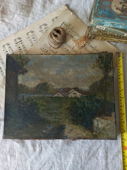 An antique oil landscape painting of a rural scene with houses, trees, and a path, displayed on a white fabric background with vintage sheet music, twine, dried flowers, and a yellow tape measure.