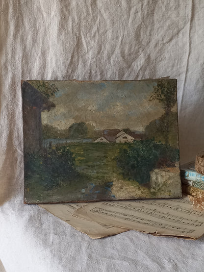An antique oil landscape painting on canvas depicting a rural scene with houses, trees, and a path, displayed on a rustic white linen cloth with old sheet music and a small stack of books as props.