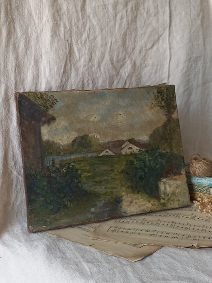 An antique oil landscape painting on canvas, depicting a rural scene with houses, trees, and a river, displayed on vintage sheet music against a draped white linen background.