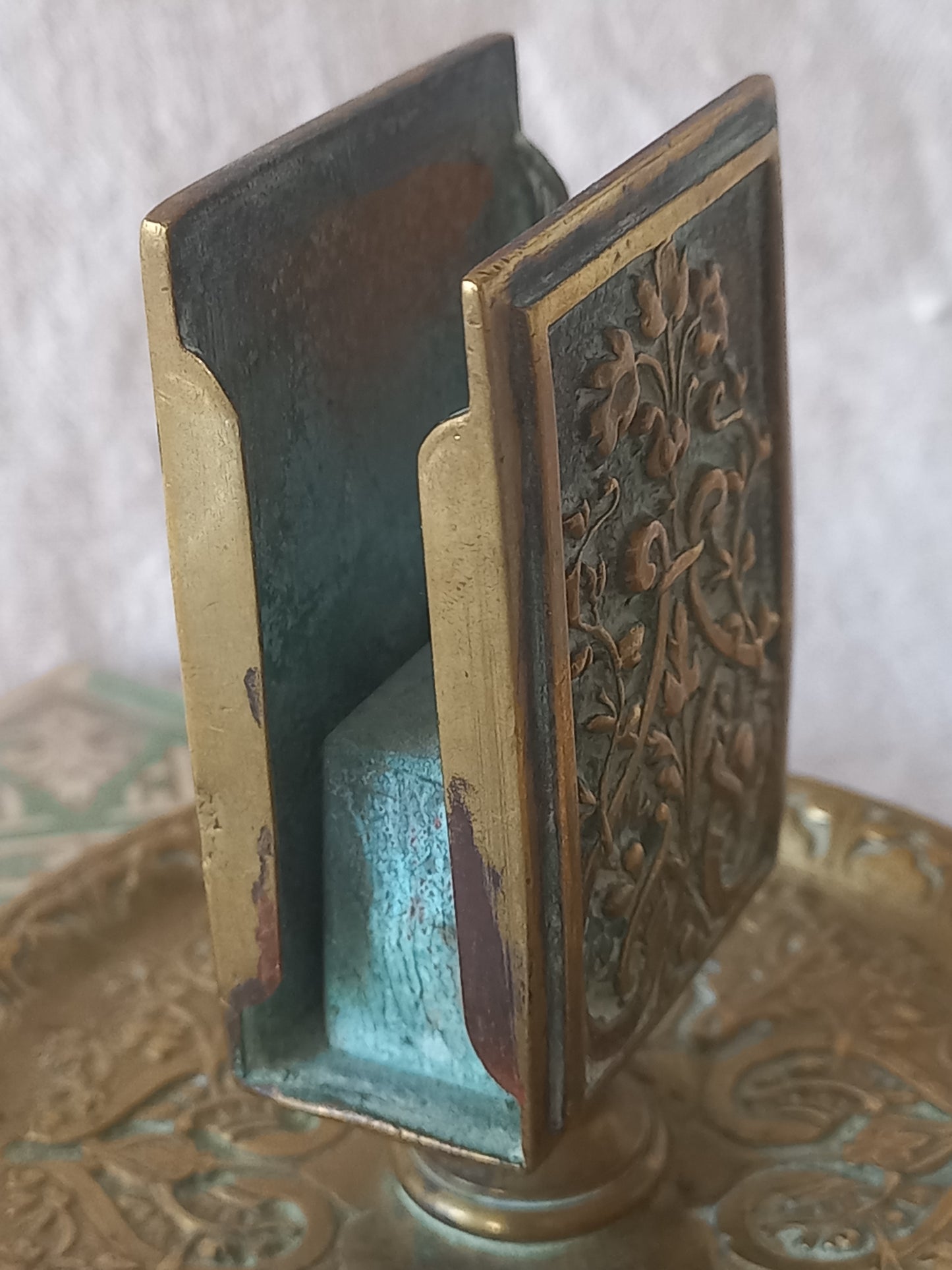 Close-up of a French antique decorative brass-coated matchbox holder in a decorative setting.