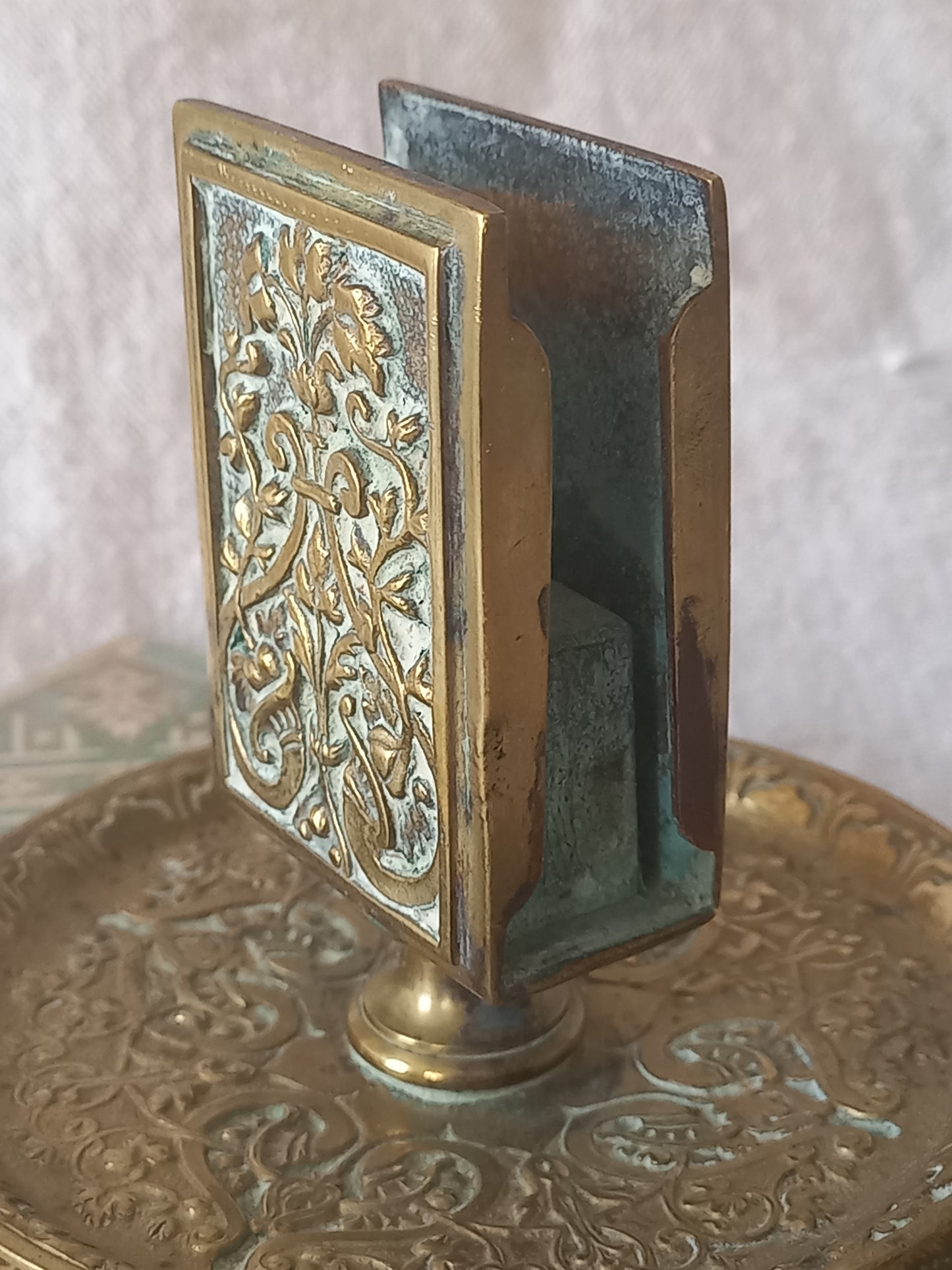 Close-up of a French antique decorative brass-coated matchbox holder in a decorative setting.