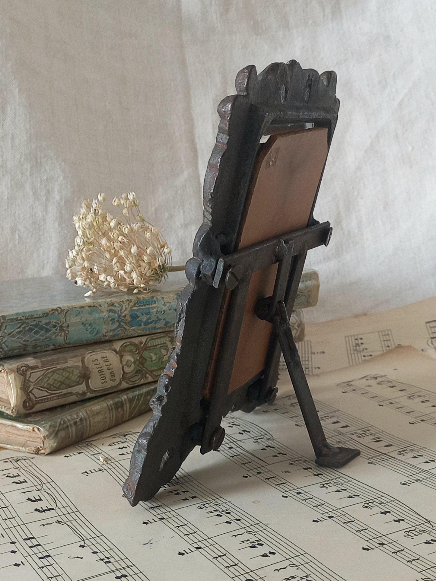 A small French antique decorative cast iron photo frame with time-worn patina. There is a glass front and a hardboard backing board. Inside is an original period photo.