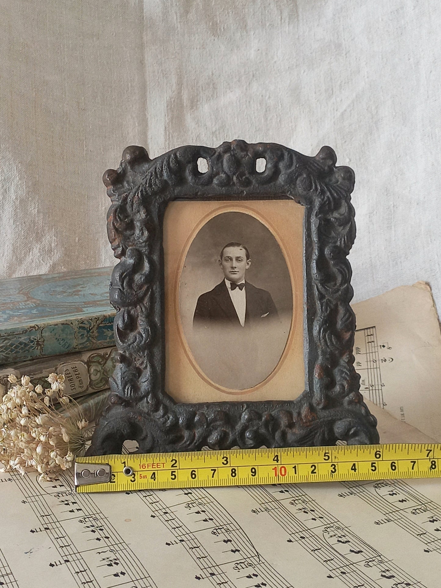 A small French antique decorative cast iron photo frame with time-worn patina. There is a glass front and a hardboard backing board. Inside is an original period photo.