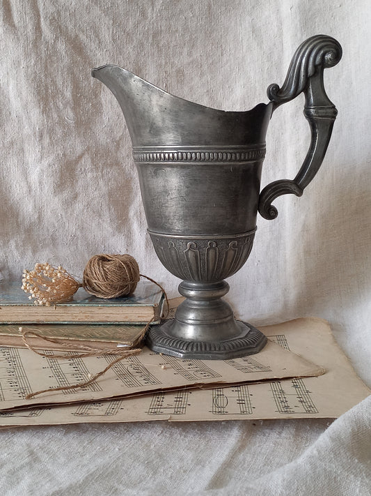 Large French antique decorative pewter jug in a decorative setting.