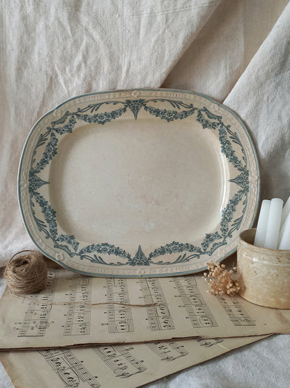 Decorative ceramic platter with blue floral patterns on a surface with sheet music and candles.
