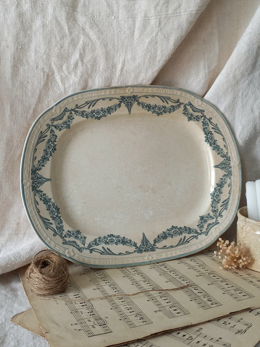 Decorative ceramic platter with blue floral patterns on a surface with old music sheets and twine.