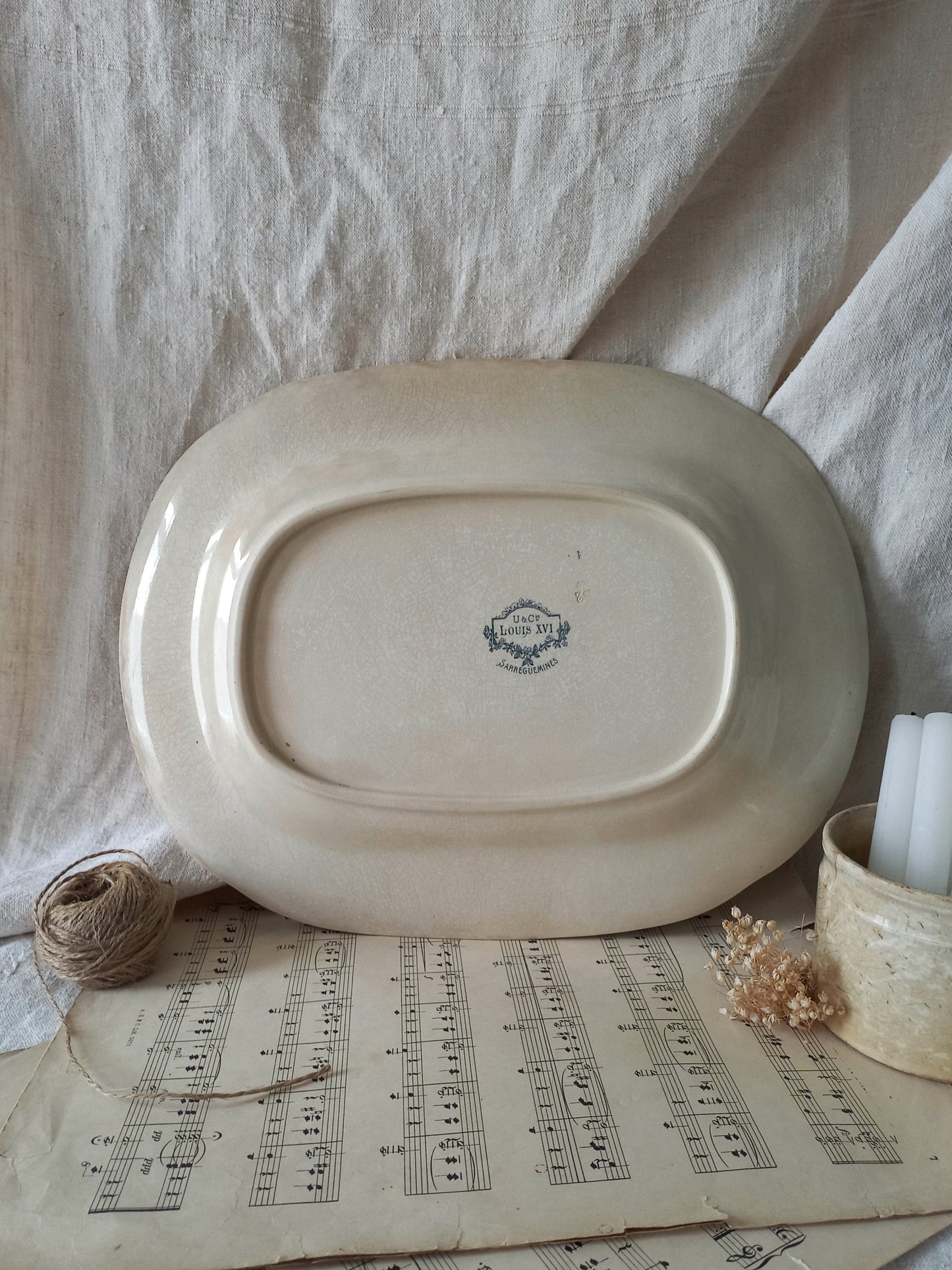 French antique aged white ironstone plate/platter with pretty blue floral pattern on a surface with sheet music and decorative items.