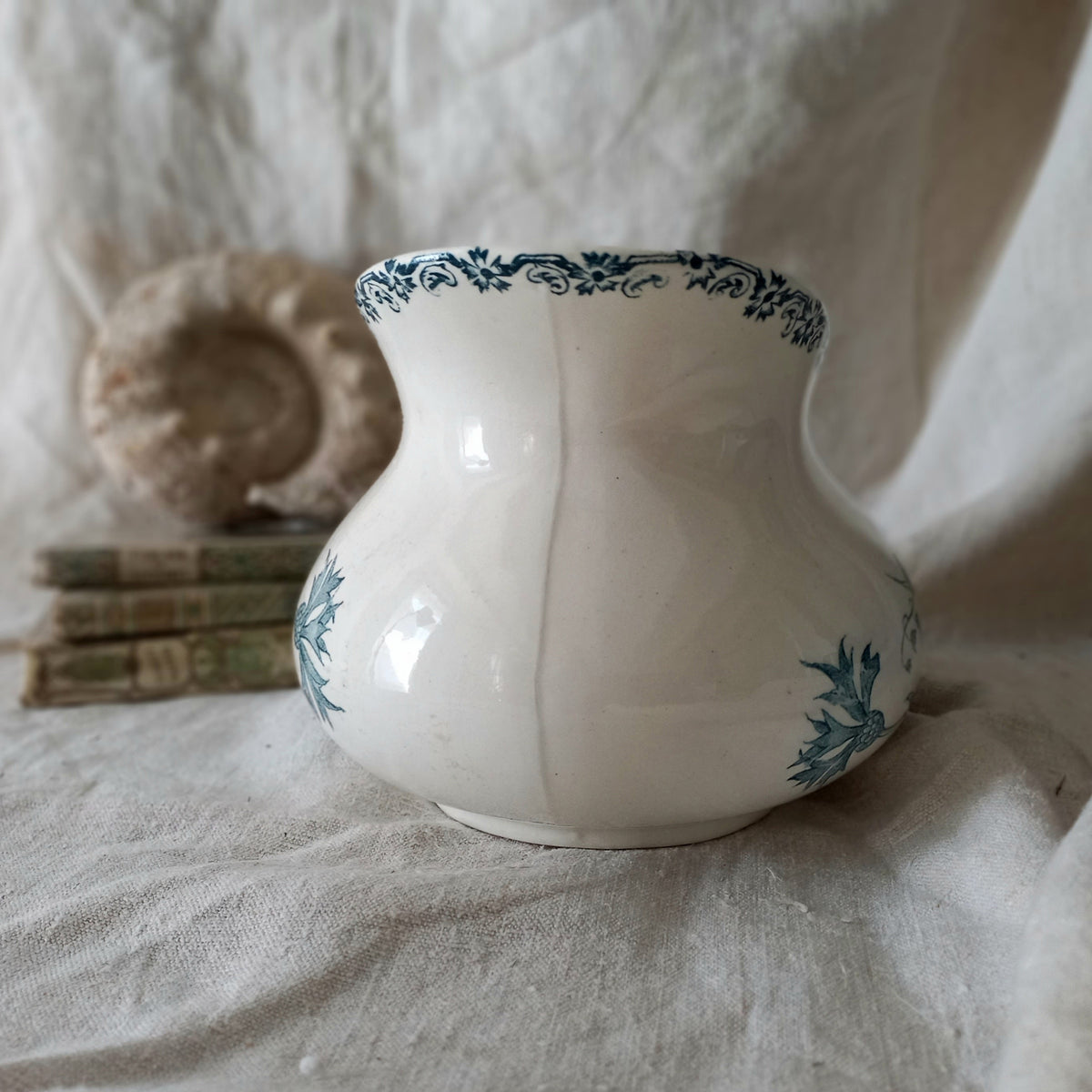 White ceramic vase with teal patterns on a textured surface
