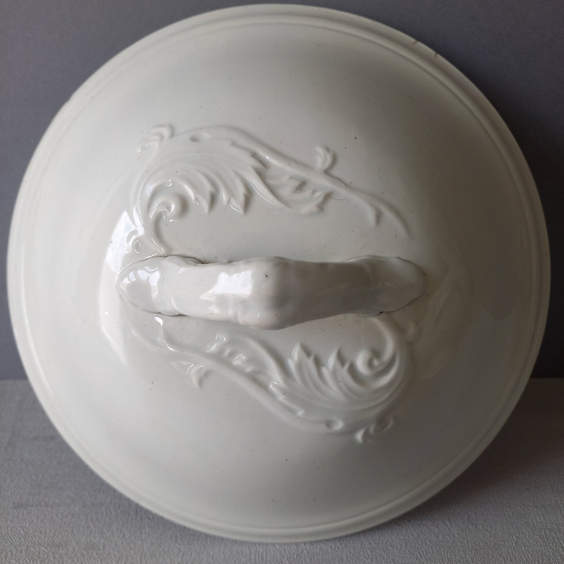 A small sized antique white ironstone soup tureen with elegant curves by French manufacturer Saint Amand et Hamage. This lovely old tureen has beautiful detailed handles either side of the tureen and on the lid. Circa late 19th to early 20th century.