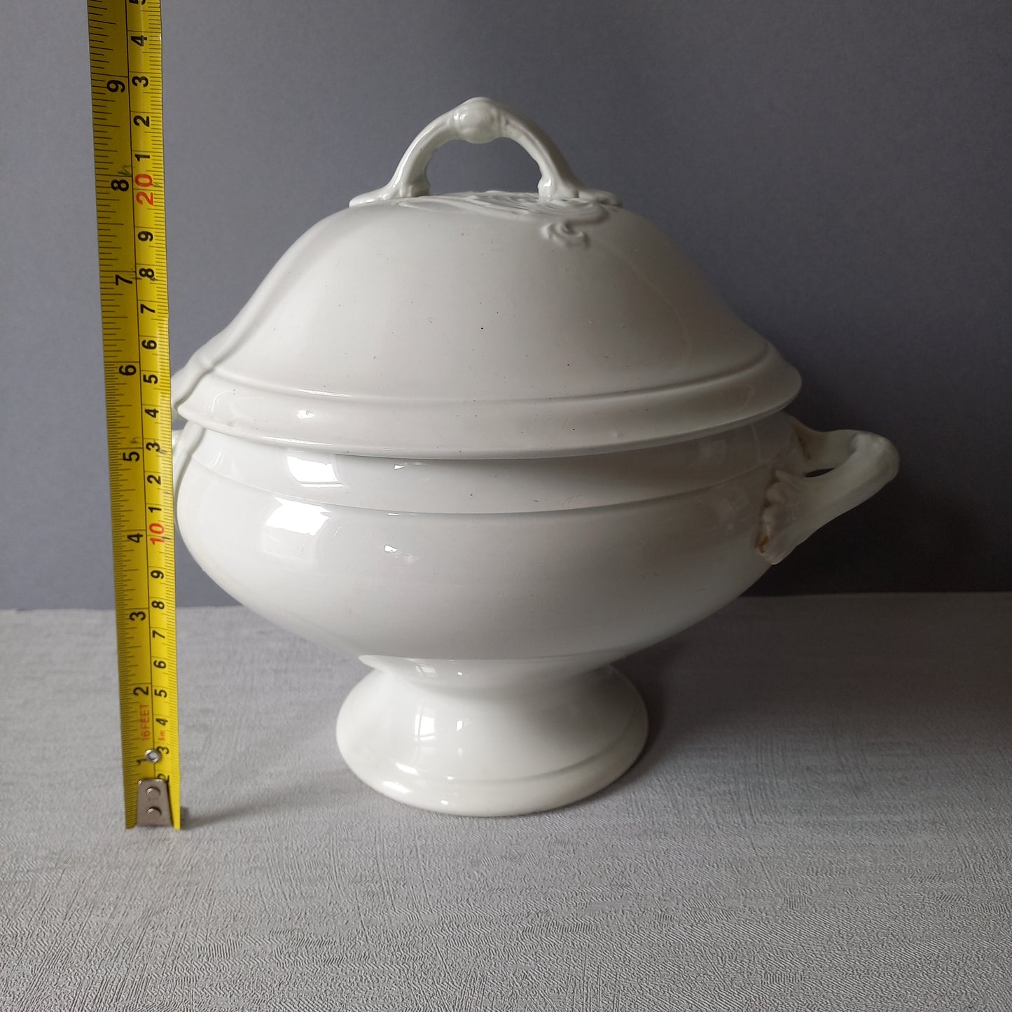 A small sized antique white ironstone soup tureen with elegant curves by French manufacturer Saint Amand et Hamage. This lovely old tureen has beautiful detailed handles either side of the tureen and on the lid. Circa late 19th to early 20th century.