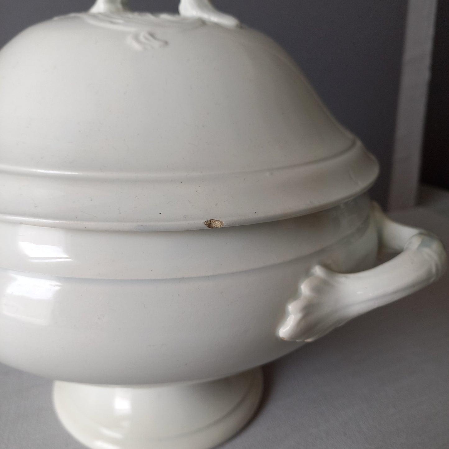 A small sized antique white ironstone soup tureen with elegant curves by French manufacturer Saint Amand et Hamage. This lovely old tureen has beautiful detailed handles either side of the tureen and on the lid. Circa late 19th to early 20th century.