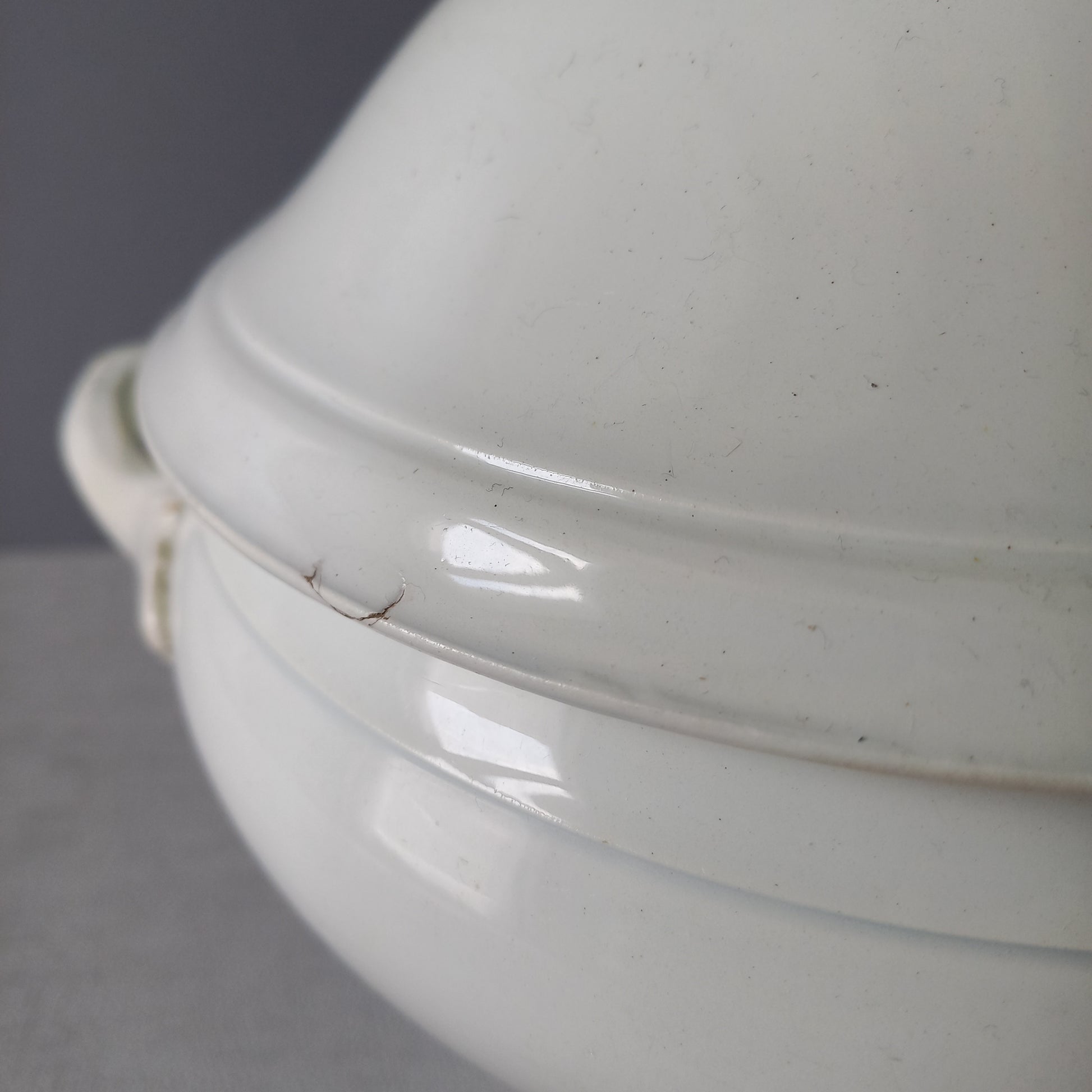 A small sized antique white ironstone soup tureen with elegant curves by French manufacturer Saint Amand et Hamage. This lovely old tureen has beautiful detailed handles either side of the tureen and on the lid. Circa late 19th to early 20th century.