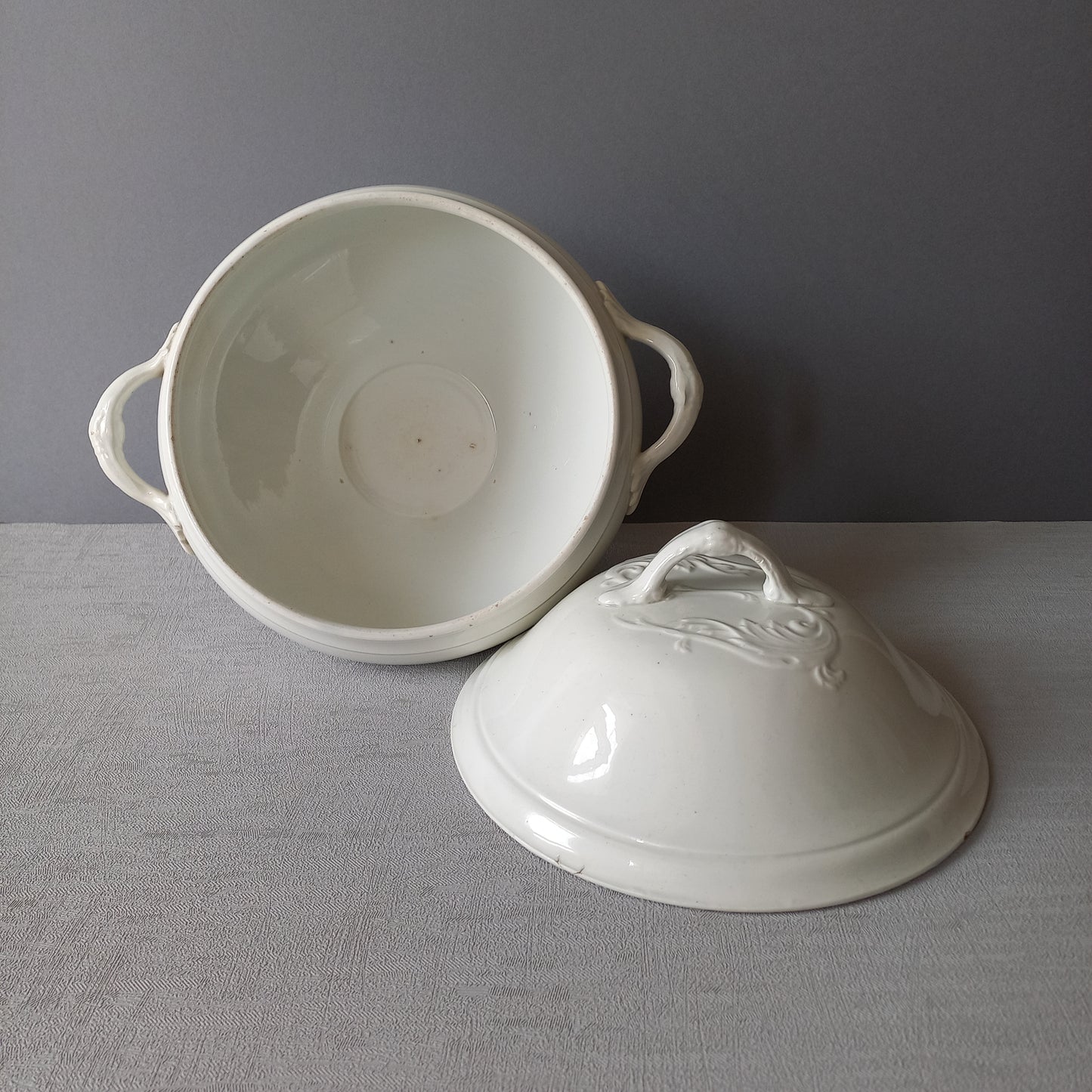 A small sized antique white ironstone soup tureen with elegant curves by French manufacturer Saint Amand et Hamage. This lovely old tureen has beautiful detailed handles either side of the tureen and on the lid. Circa late 19th to early 20th century.