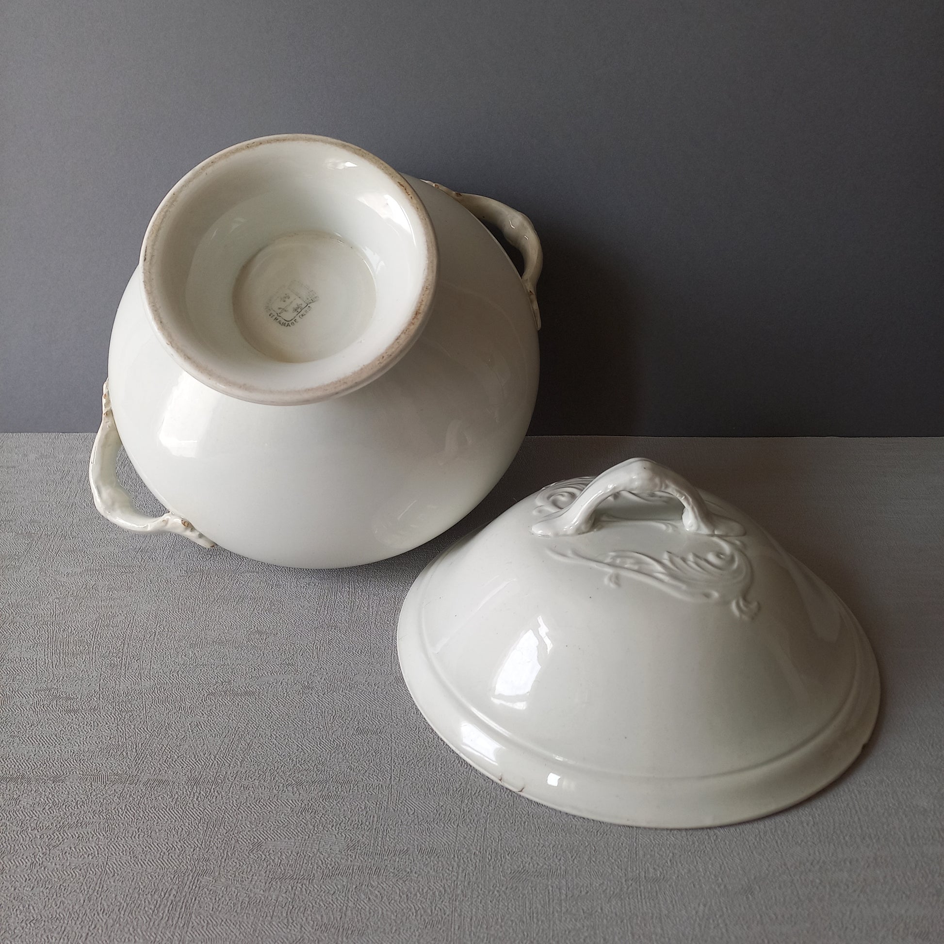 A small sized antique white ironstone soup tureen with elegant curves by French manufacturer Saint Amand et Hamage. This lovely old tureen has beautiful detailed handles either side of the tureen and on the lid. Circa late 19th to early 20th century.