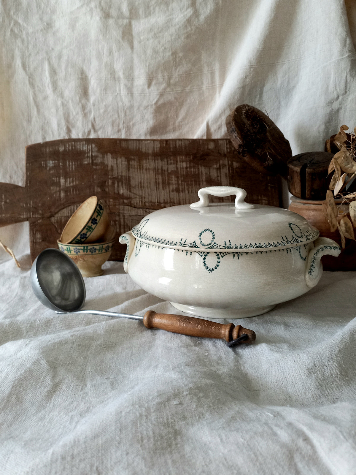 White ceramic tureen with green patterns on a white fabric background