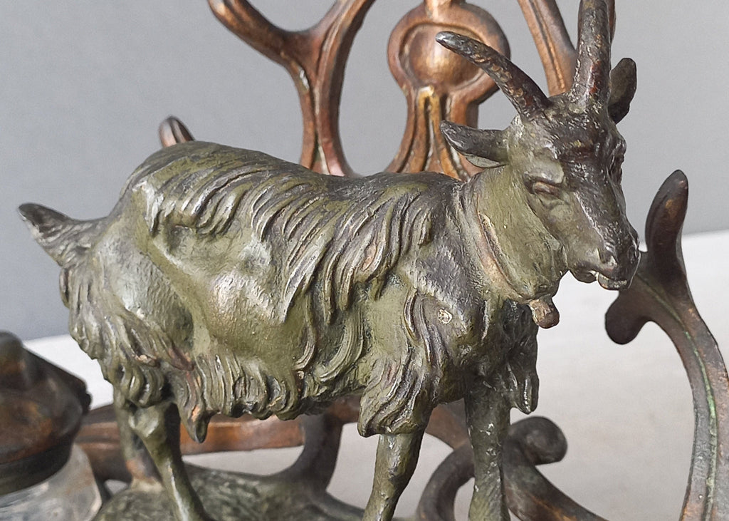 A stunning French art nouveau double inkwell with a goat figurine.

This wonderful antique inkwell has been sculpted in metal and signed by the artist (see photos). Behind the beautiful goat figurine are two pen rests and either side of the goat are two small glass ink pots with decorative metal lids.

The metal is finished in a lovely shade of green that has worn over time with traces of gold colour beneath - it has a wonderful patina of time all over it.