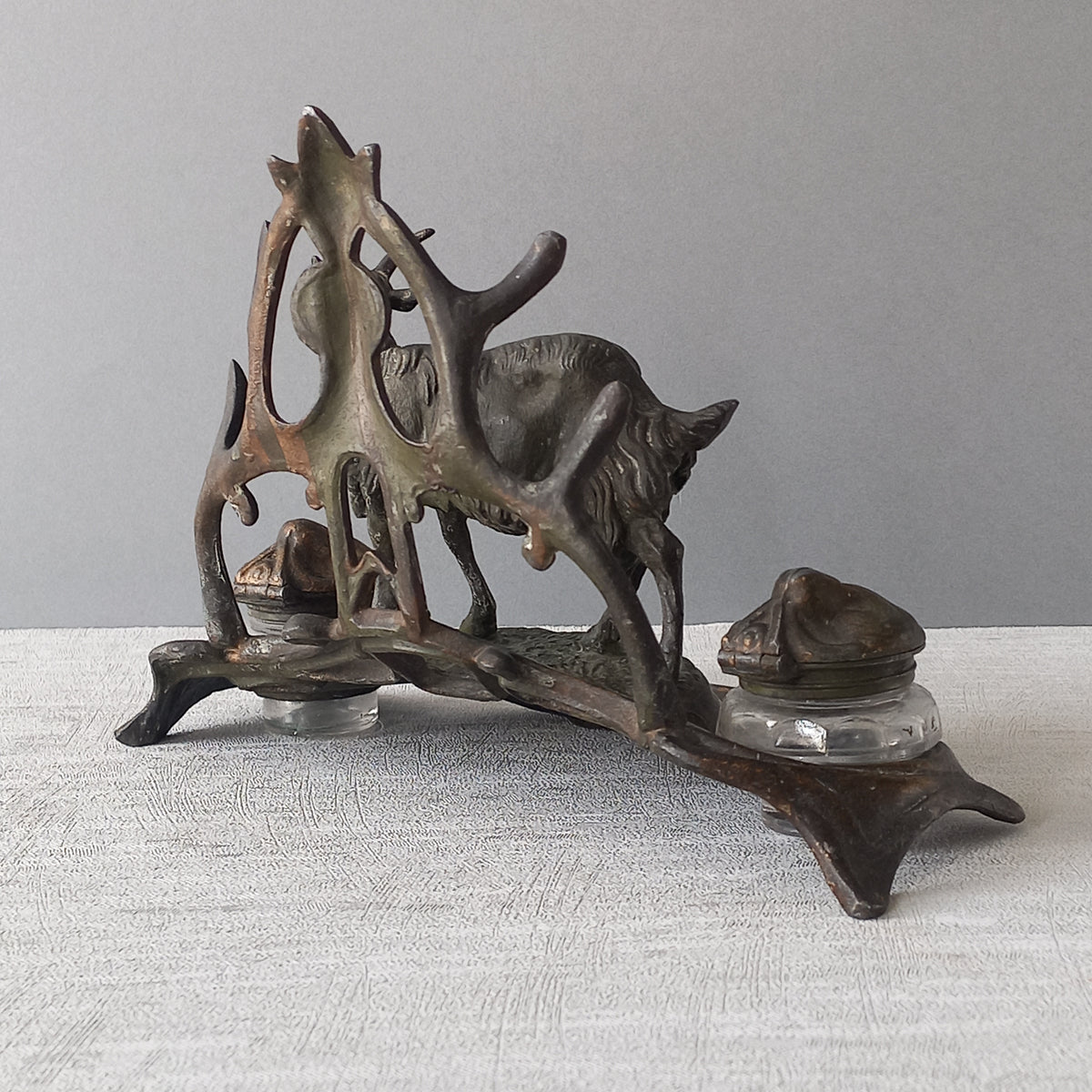 A stunning French art nouveau double inkwell with a goat figurine.

This wonderful antique inkwell has been sculpted in metal and signed by the artist (see photos). Behind the beautiful goat figurine are two pen rests and either side of the goat are two small glass ink pots with decorative metal lids.

The metal is finished in a lovely shade of green that has worn over time with traces of gold colour beneath - it has a wonderful patina of time all over it.