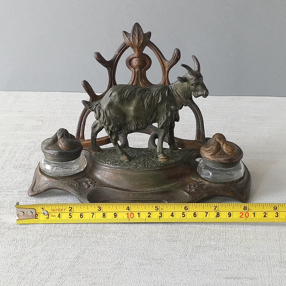 A stunning French art nouveau double inkwell with a goat figurine.

This wonderful antique inkwell has been sculpted in metal and signed by the artist (see photos). Behind the beautiful goat figurine are two pen rests and either side of the goat are two small glass ink pots with decorative metal lids.

The metal is finished in a lovely shade of green that has worn over time with traces of gold colour beneath - it has a wonderful patina of time all over it.