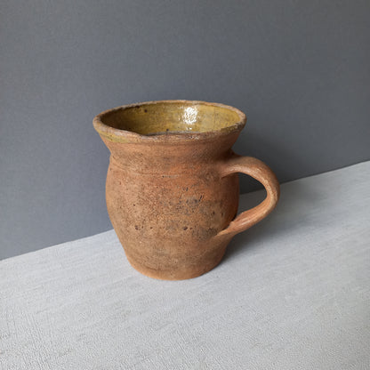 Small rustic vintage pottery jug with ochre glazed interior from France