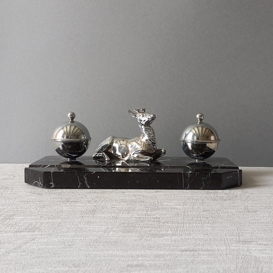 A French art deco double inkwell with fawn or young deer figurine. This is a quality, heavy piece of desk decor, the base, which has a place to rest your pen, is made from solid black marble while the inkwells and fawn deer figure are made from polished metal. Inside each metal pot there is no longer any type of liner to hold ink, if in fact if ever had any in the first place. In summary, a wonderful find and a magnificent decorative ornament from France.