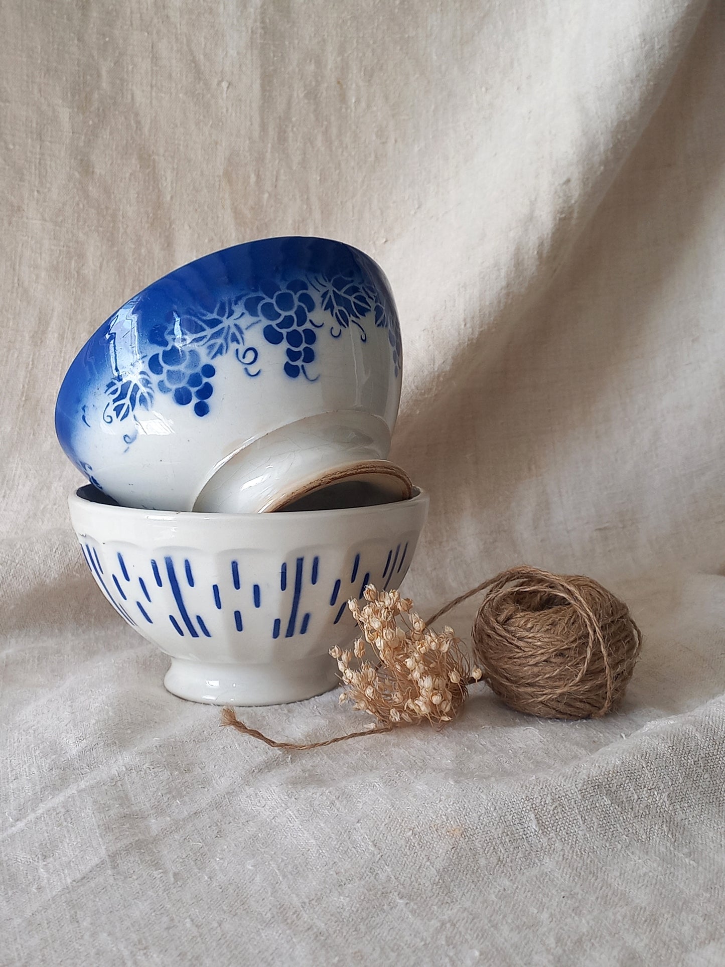 Two ceramic bowls with blue patterns on a textured surface with twine.