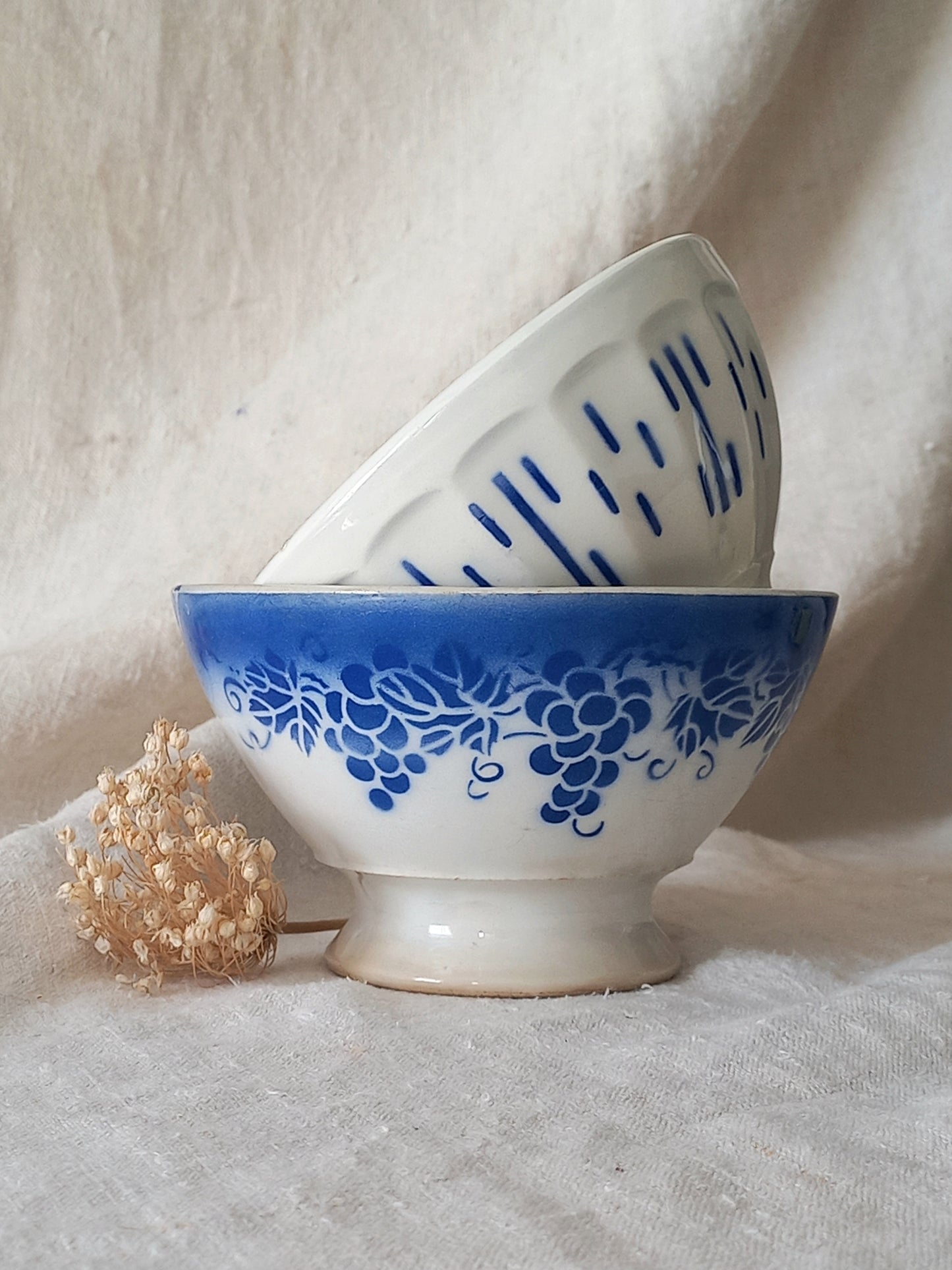 Two ceramic bowls with blue patterns on a light fabric background