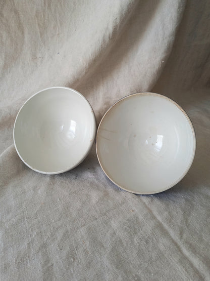 Interiors of blue and white vintage ceramic cafe au lait bowls on a light fabric background.
