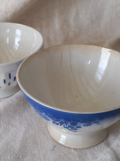 Blue and white vintage ceramic cafe au lait bowl with floral patterns on a light fabric background.