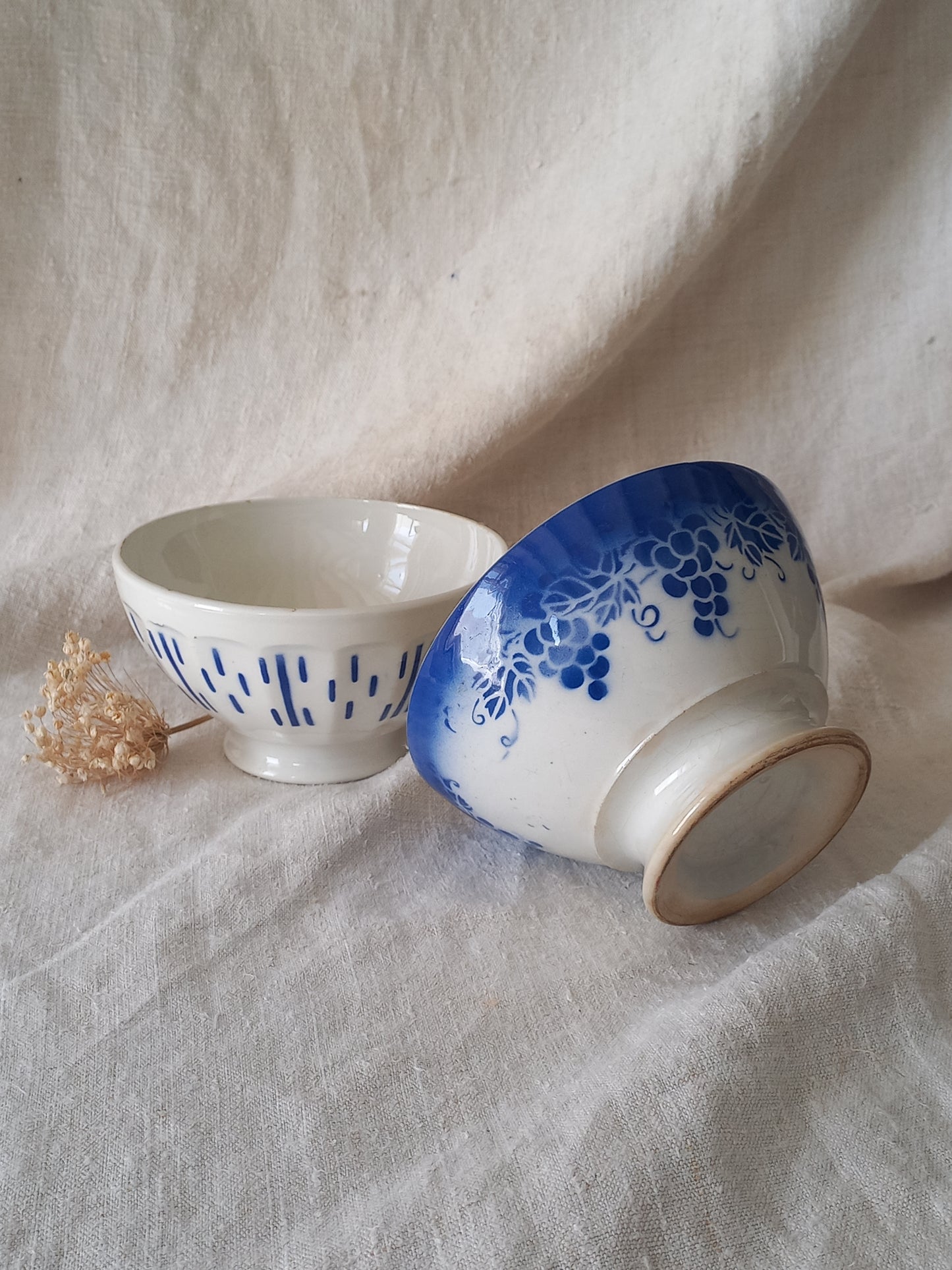 Two ceramic cups with blue floral patterns on a textured fabric background