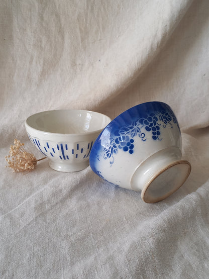Two ceramic cups with blue floral patterns on a textured fabric background