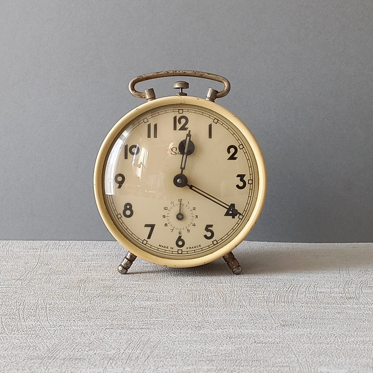 A wonderful French vintage alarm clock in a lovely shade of cream called 'Scout'.

This old clock is in working condition including the alarm and has a nice soothing ticking sound too.

The clock's metal case has a finish that has slight discoloring in places and paint chips (mainly to the rear - see photos) which gives it character.

In summary, a nice vintage alarm clock from France!