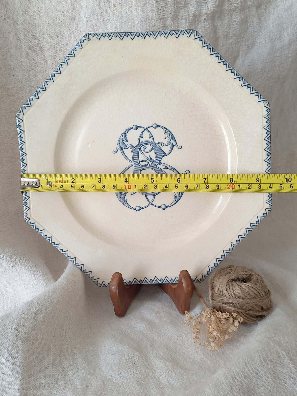 French antique ironstone octagonal plate with the monogram/initial 'B' and a tape measure for reference.