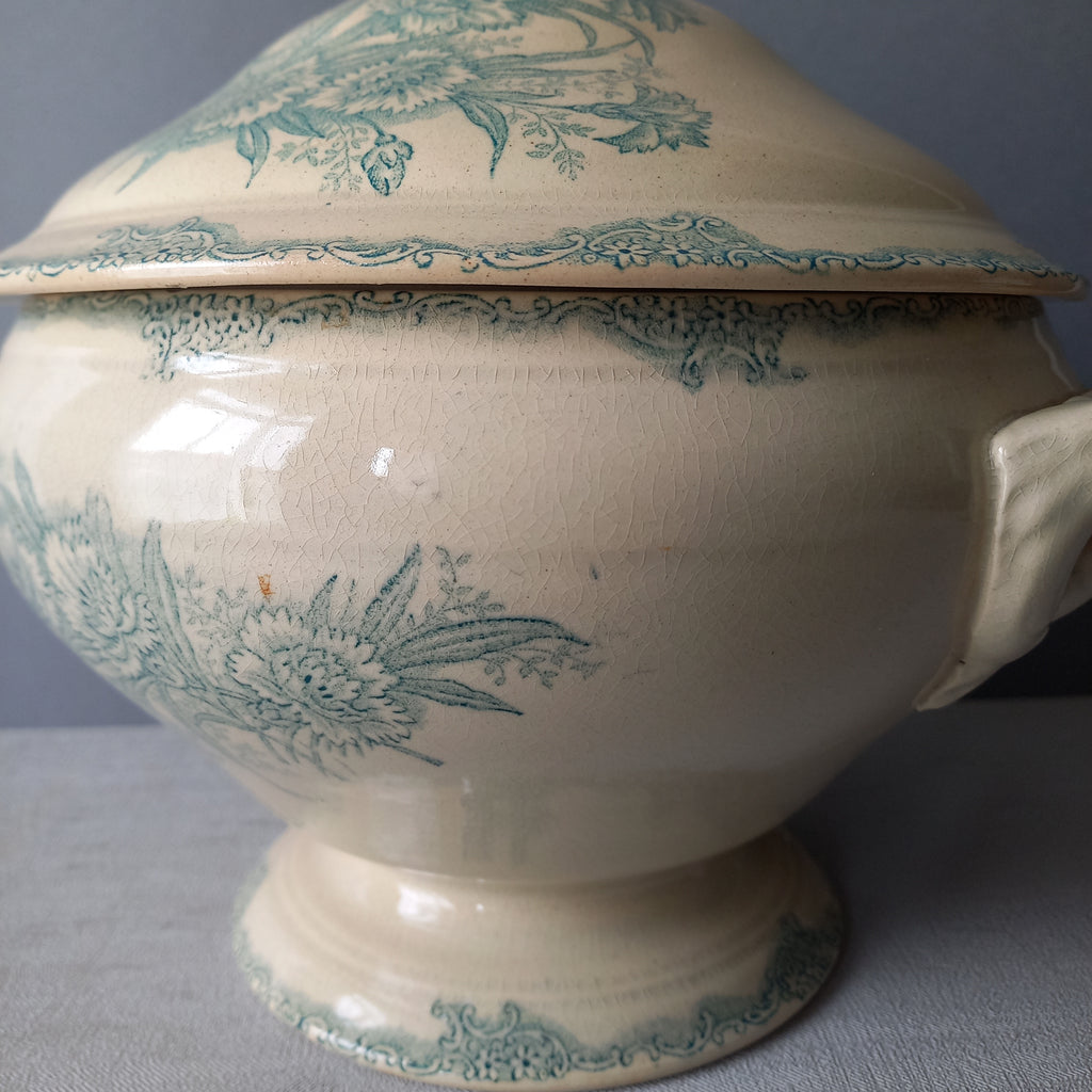 A pretty antique ironstone soup tureen with aged and faded floral transfer pattern in a beautiful shade of blue green or teal. Over time this wonderful old tureen has developed a pleasing faded creamy white finish. In summary, a beautiful piece of authentic antique ironstone from France.