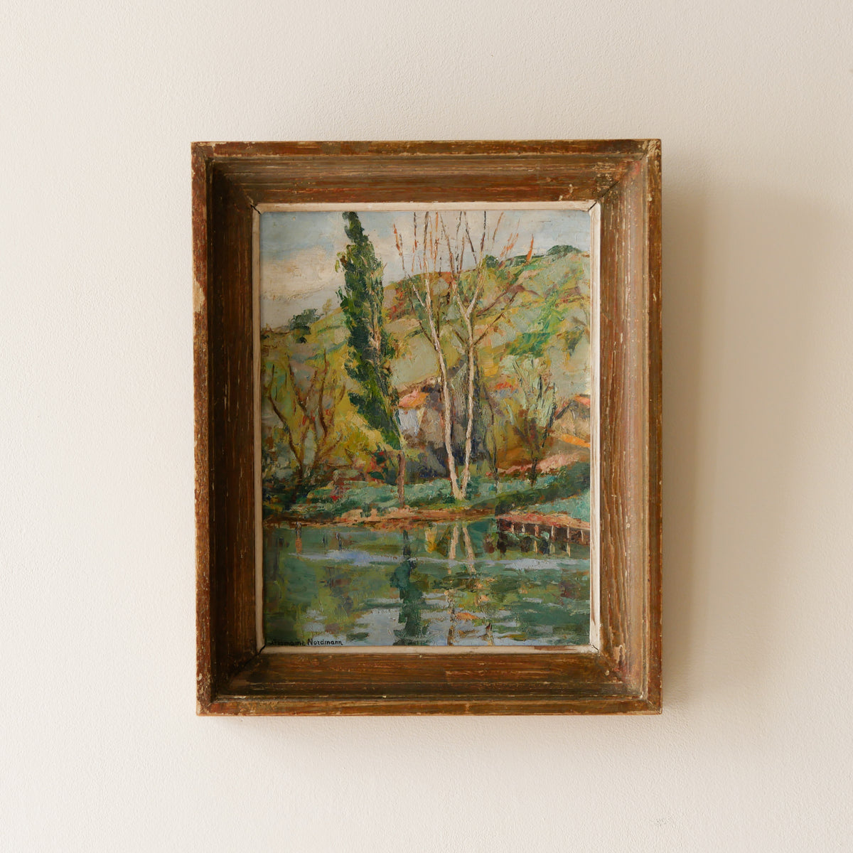 An original vintage landscape oil painting depicting a charming country home in among a wooded area with hills in the background. In the foreground a gentle river reflects the trees in the background.

The painting has been painted by an experienced artist with confident brush strokes - a really wonderful piece of original art.

The painting is presented in an old worn wooden frame which we love and think others will too - it really suits this piece. 