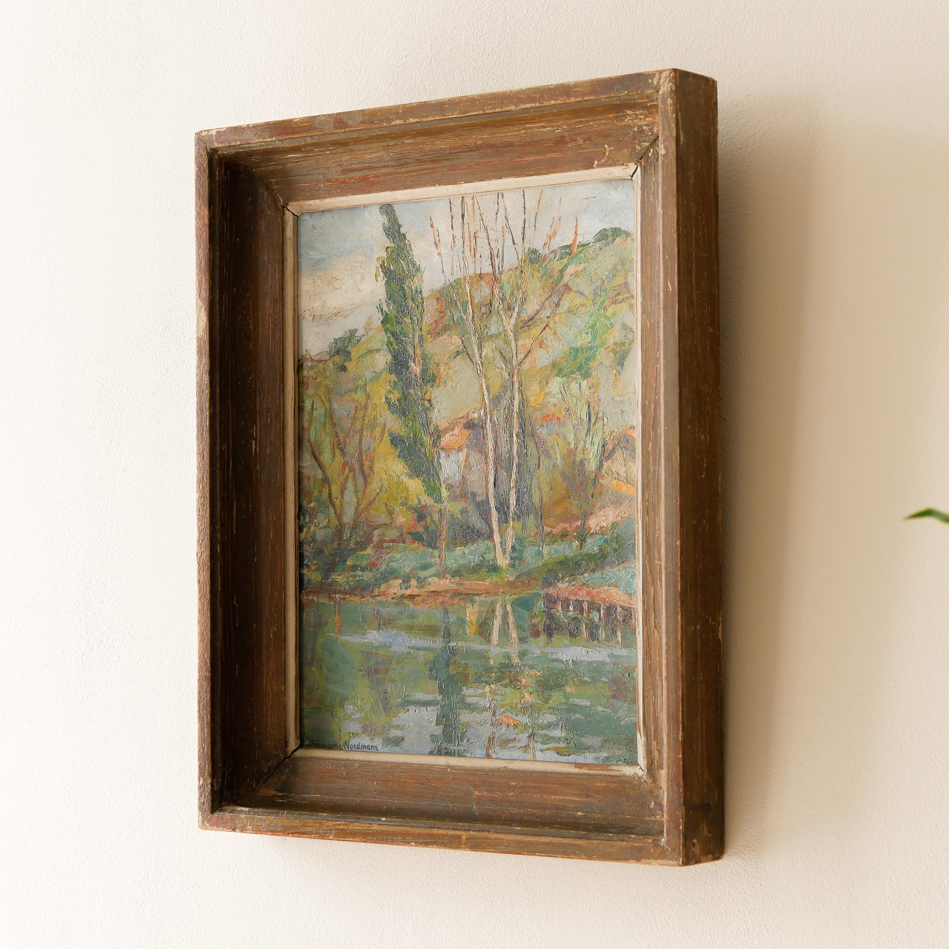 An original vintage landscape oil painting depicting a charming country home in among a wooded area with hills in the background. In the foreground a gentle river reflects the trees in the background.

The painting has been painted by an experienced artist with confident brush strokes - a really wonderful piece of original art.

The painting is presented in an old worn wooden frame which we love and think others will too - it really suits this piece. 