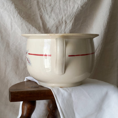 White ceramic bowl with red stripe on a wooden stool against a textured white background