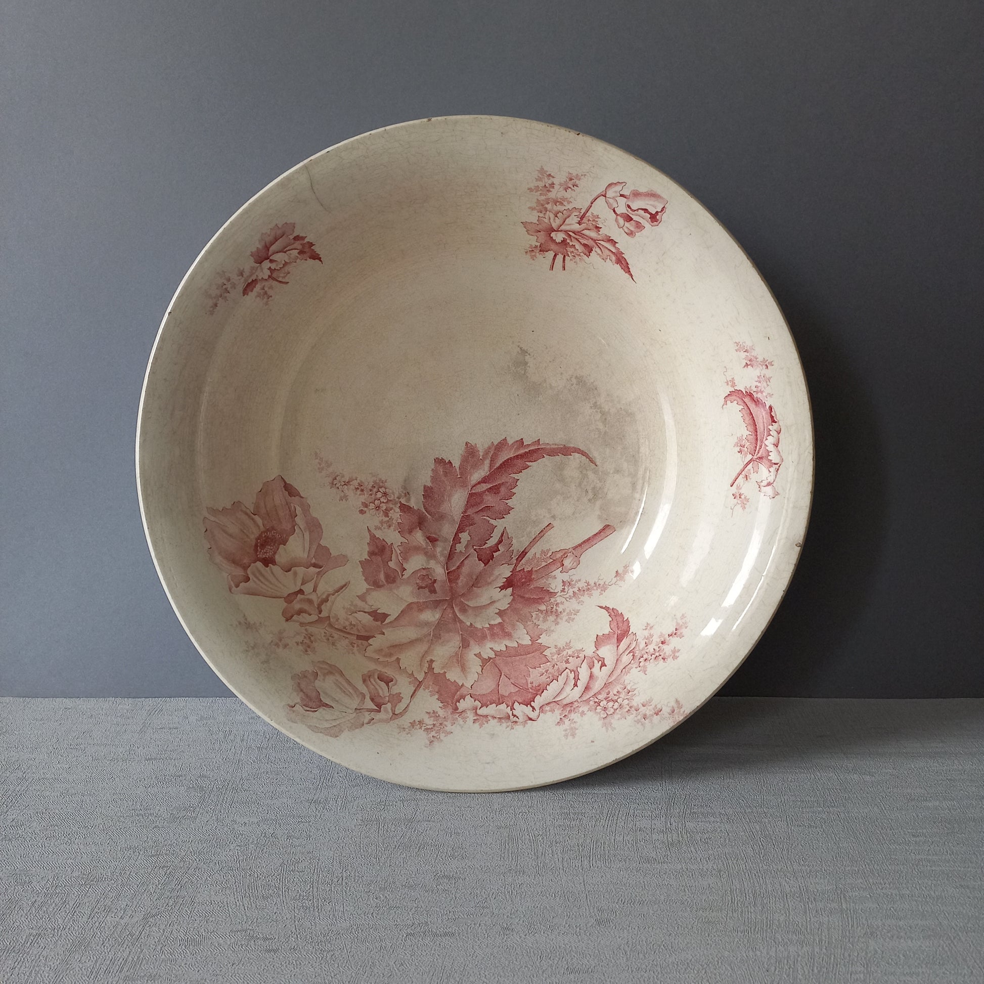 A large French vintage ironstone bowl with beautiful deep pink floral pattern on a creamy white base colour. Over the years this old bowl has aged nicely with crazing, tea-staining, and the odd little imperfections that show this as an authentic antique piece.

There is a maker's mark on the base. Circa. late 1800s/early 1900s.