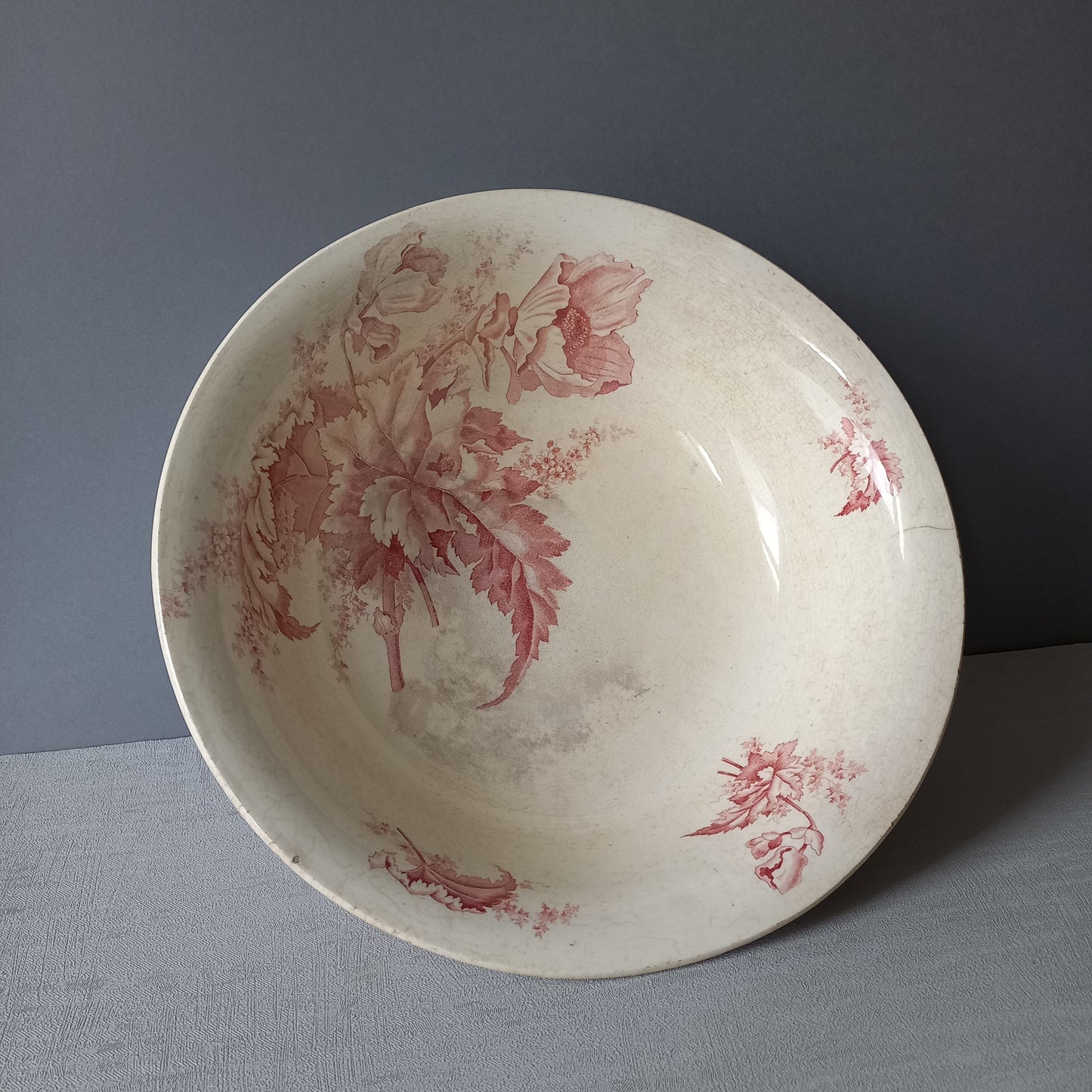 A large French vintage ironstone bowl with beautiful deep pink floral pattern on a creamy white base colour. Over the years this old bowl has aged nicely with crazing, tea-staining, and the odd little imperfections that show this as an authentic antique piece.

There is a maker's mark on the base. Circa. late 1800s/early 1900s.