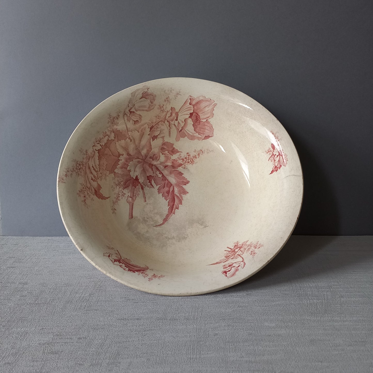 A large French vintage ironstone bowl with beautiful deep pink floral pattern on a creamy white base colour. Over the years this old bowl has aged nicely with crazing, tea-staining, and the odd little imperfections that show this as an authentic antique piece.

There is a maker's mark on the base. Circa. late 1800s/early 1900s.