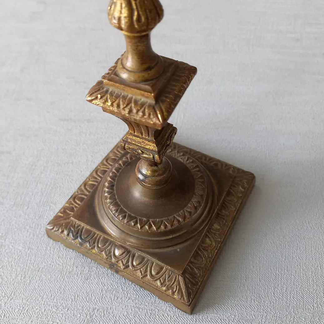 Decorative bronze candlestick on a textured surface with a gray 