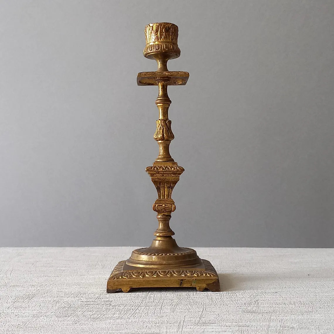Decorative bronze candlestick on a textured surface with a gray 