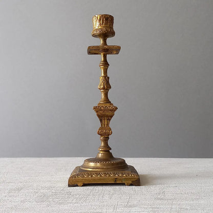 Decorative bronze candlestick on a textured surface with a gray 