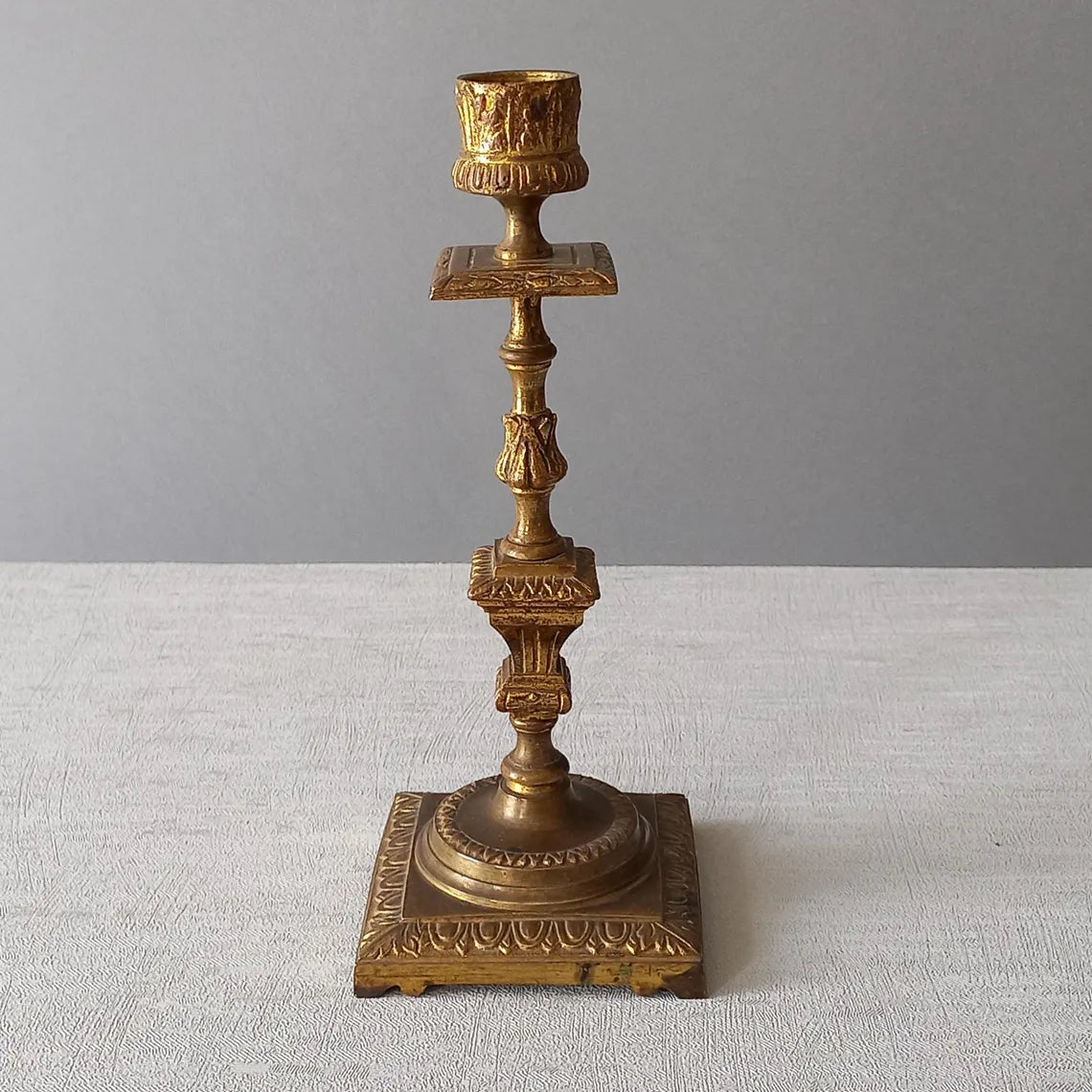 Decorative bronze candlestick on a textured surface with a gray 