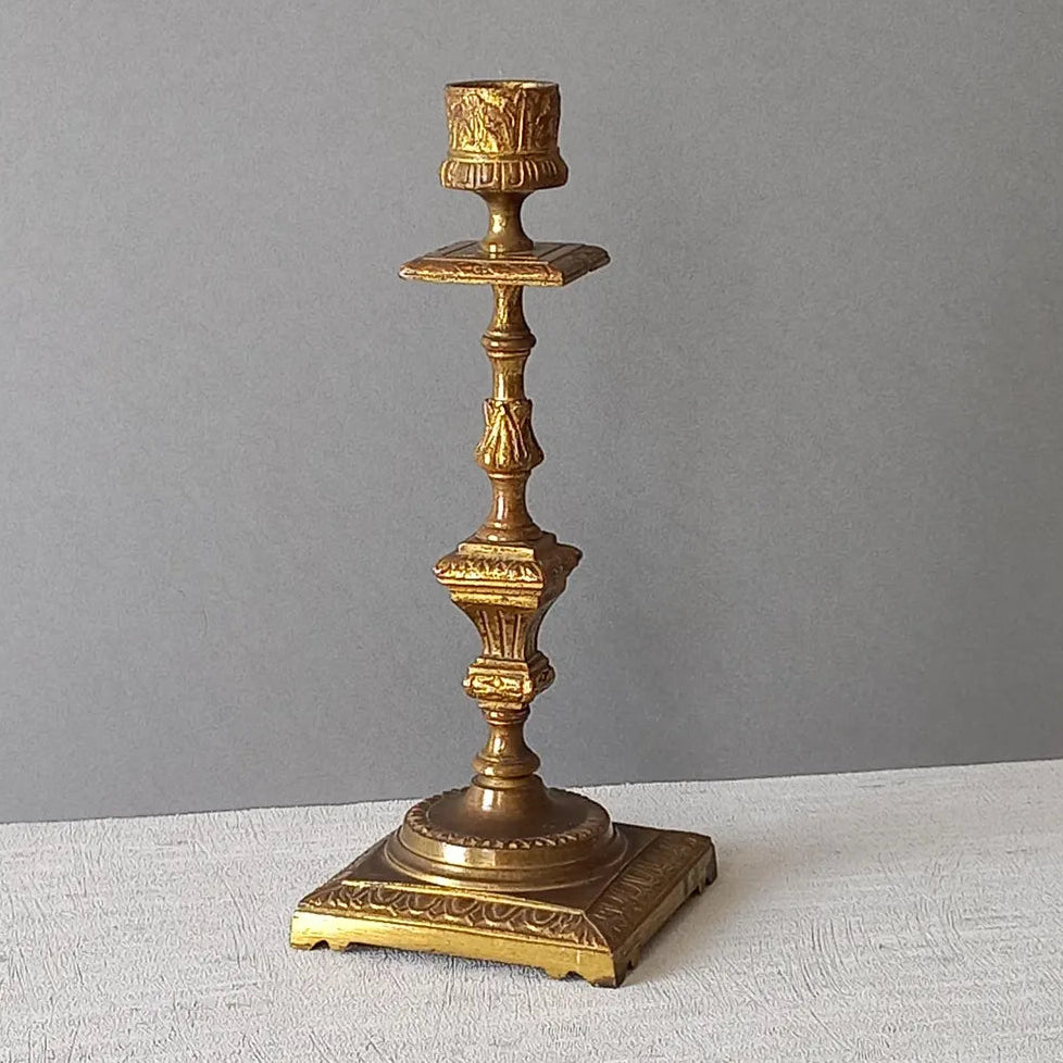 Decorative gold candlestick on a gray surface with a gray background