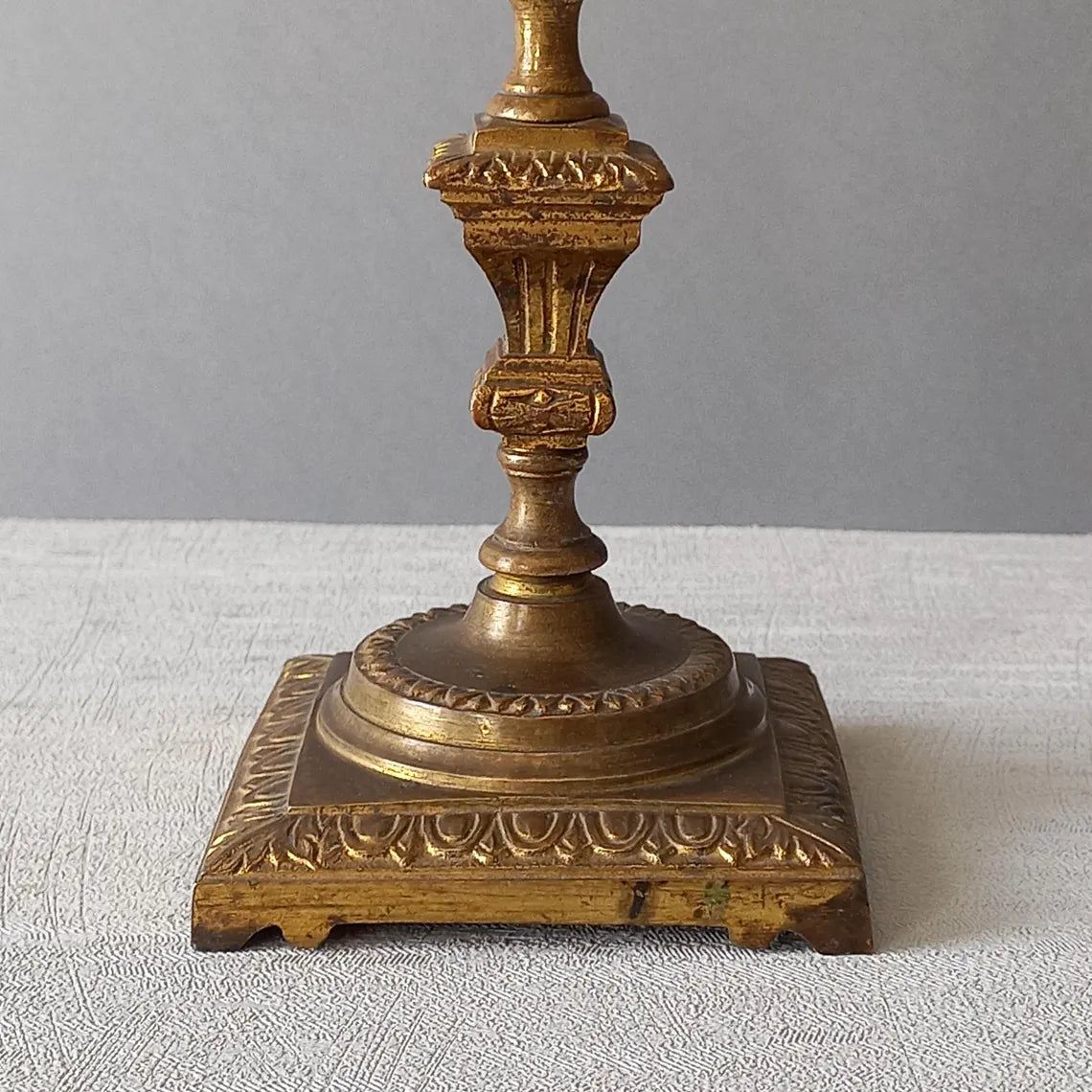 Decorative bronze candlestick on a textured surface with a gray 