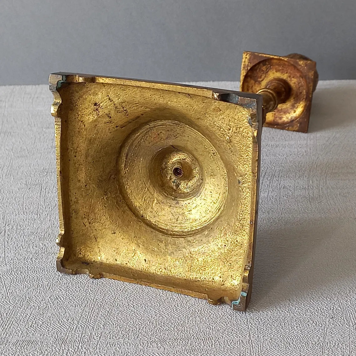 Decorative bronze candlestick on a textured surface with a gray 
